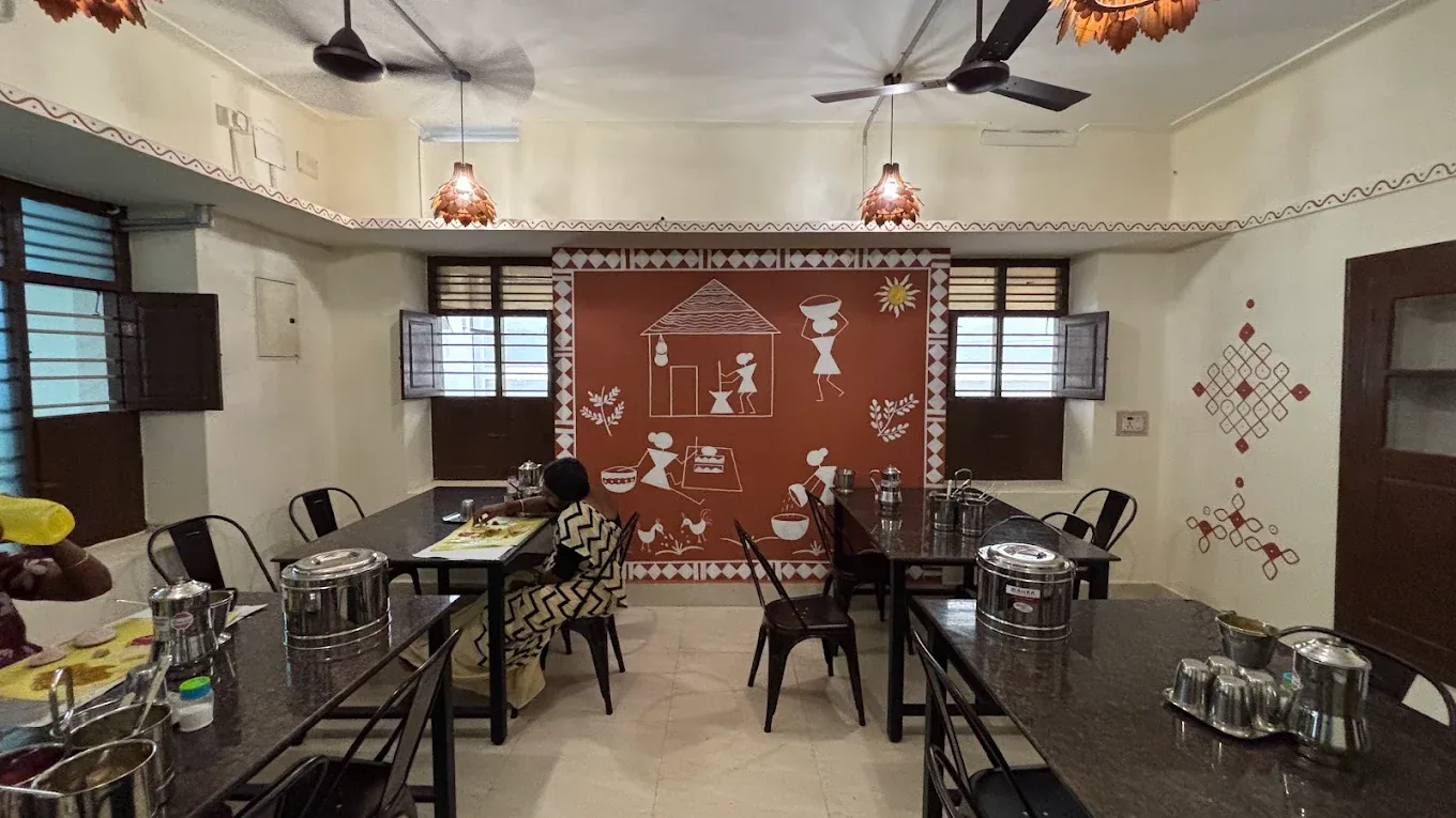 Dining tables and hand-painted village mural at Sathvamirtham