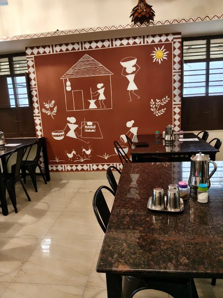 Dining tables inside Sathvamirtham with traditional wall art