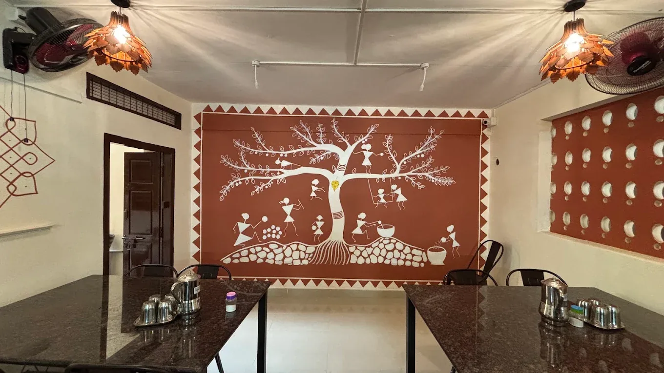 Warm restaurant interior with Sathvamirtham's hand-painted traditional mural